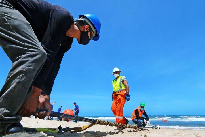 Men laying the EllaLink cable at the beach of Praia do Futuro, Fortaleza, Brazil